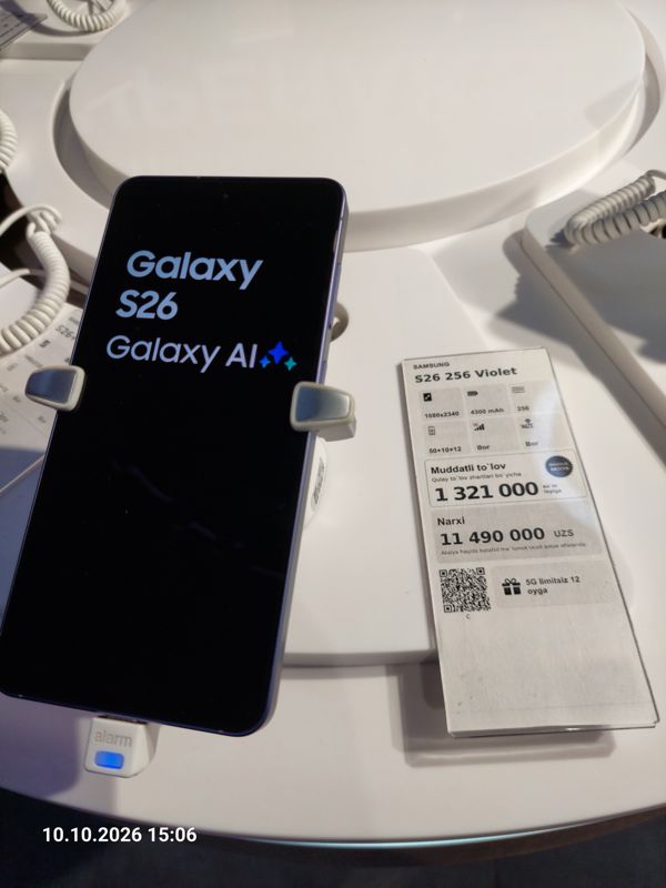 Смартфон Samsung Galaxy S26 в держателе с сигнализацией на витрине Ucell, рядом ценник-карточка: SAMSUNG S26 256 Violet, плашка «Maxsus aksiya» и подарок «5G limitsiz 12 oyga»