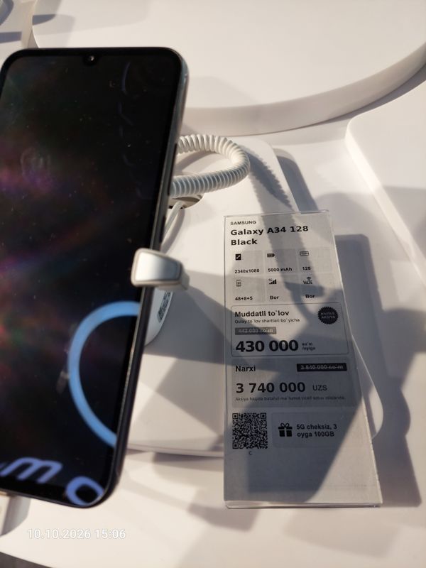 Смартфон Samsung Galaxy A34 в держателе с сигнализацией на витрине Ucell, рядом ценник-карточка: SAMSUNG Galaxy A34 128 Black, плашка «Maxsus aksiya», 3 740 000 сум, перечёркнутая прежняя цена 3 840 000