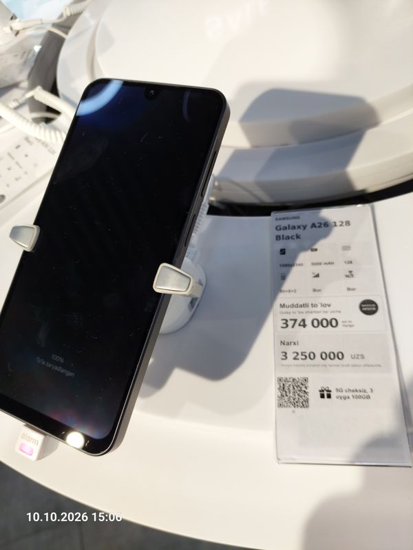 Смартфон Samsung Galaxy A26 в держателе с сигнализацией на витрине Ucell, рядом ценник-карточка: SAMSUNG Galaxy A26 128 Black, плашка «Maxsus aksiya», 3 250 000 сум