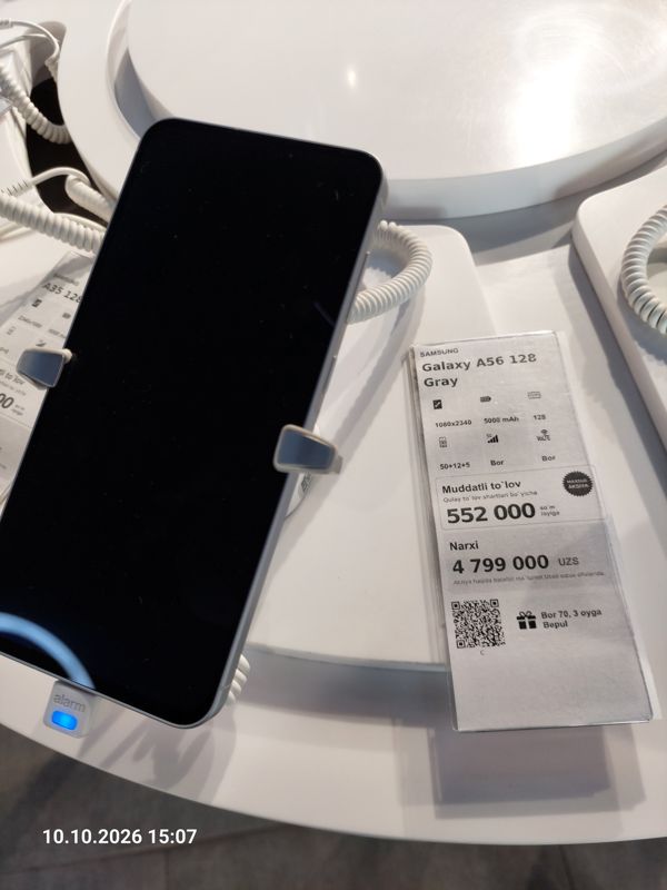 Смартфон Samsung Galaxy A56 на подставке с ценником Ucell: плашка «Maxsus aksiya» и подарок «Bor 70, 3 oyga Bepul»