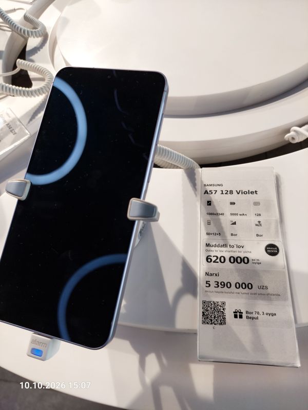 Смартфон Samsung A57 на подставке с ценником Ucell: плашка «Maxsus aksiya» и подарок «Bor 70, 3 oyga Bepul»