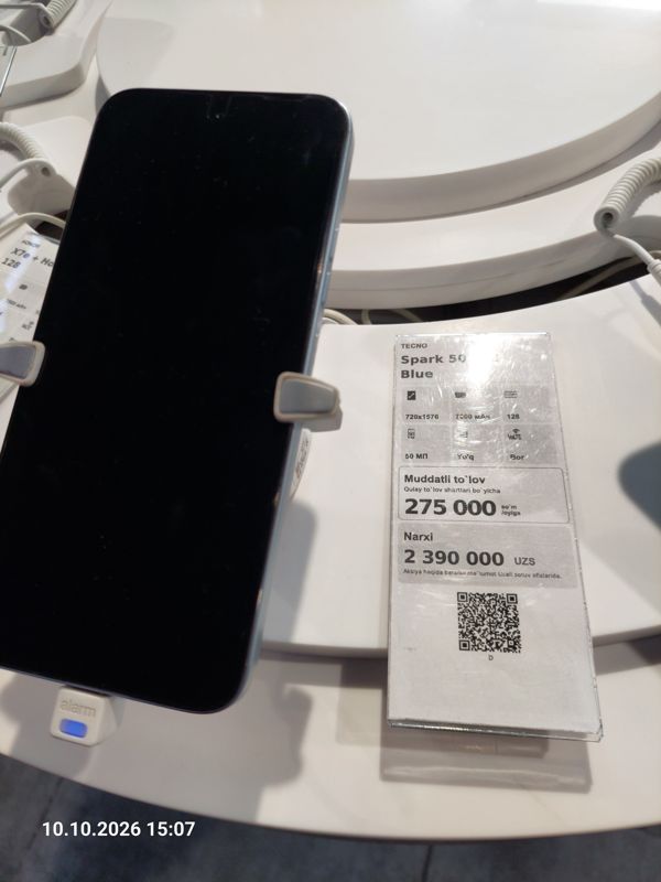 Смартфон Tecno Spark 50 в держателе с сигнализацией на витрине Ucell, рядом ценник-карточка: Spark 50 128 Blue, 7000 мАч, цена 2 390 000 сум