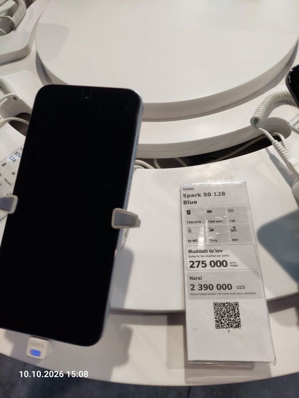 Смартфон Tecno Spark 50 в держателе с сигнализацией на витрине Ucell, рядом ценник-карточка: TECNO Spark 50 128 Blue, 7000 мАч, цена 2 390 000 сум
