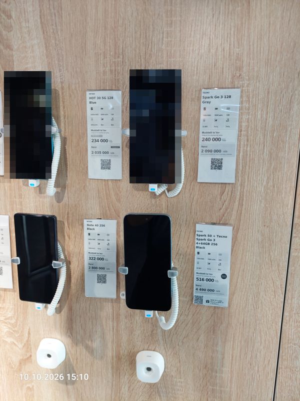 Стенд смартфонов на противокражных держателях в офисе Ucell: ценники-карточки Infinix HOT 30 5G, Tecno Spark Go 3, Infinix Note 40, Tecno Spark 50 + Spark Go 3