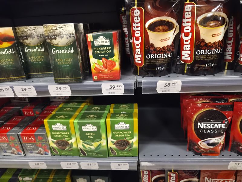 Полки с чаем (Greenfield, Ahmad Tea, Tess) и растворимым кофе (MacCoffee Original, Nescafe Classic); ряды белых ценников на чай и кофе