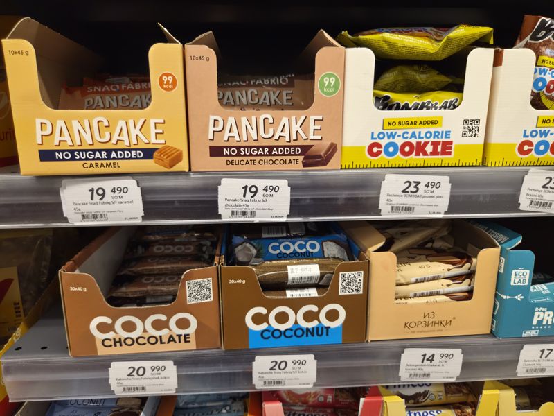 Полки с протеиновыми батончиками и печеньем: Snaq Fabriq Pancake и Coco, Bombbar, «Из Корзинки», ECO LAB, ценники от 12.10.2026