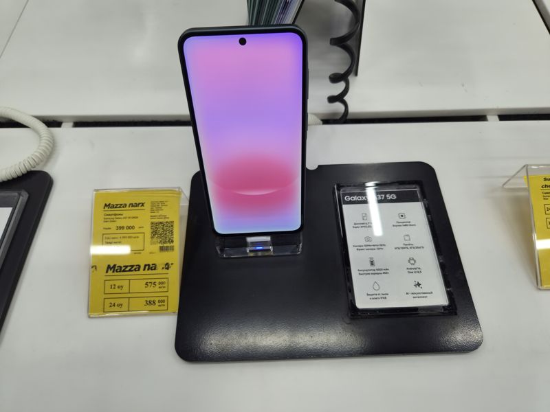 Смартфон Samsung Galaxy A37 5G (Dark Green) на подставке с карточкой характеристик, жёлтый ценник «Mazza narx» со старой ценой и рассрочкой на 12 и 24 месяца