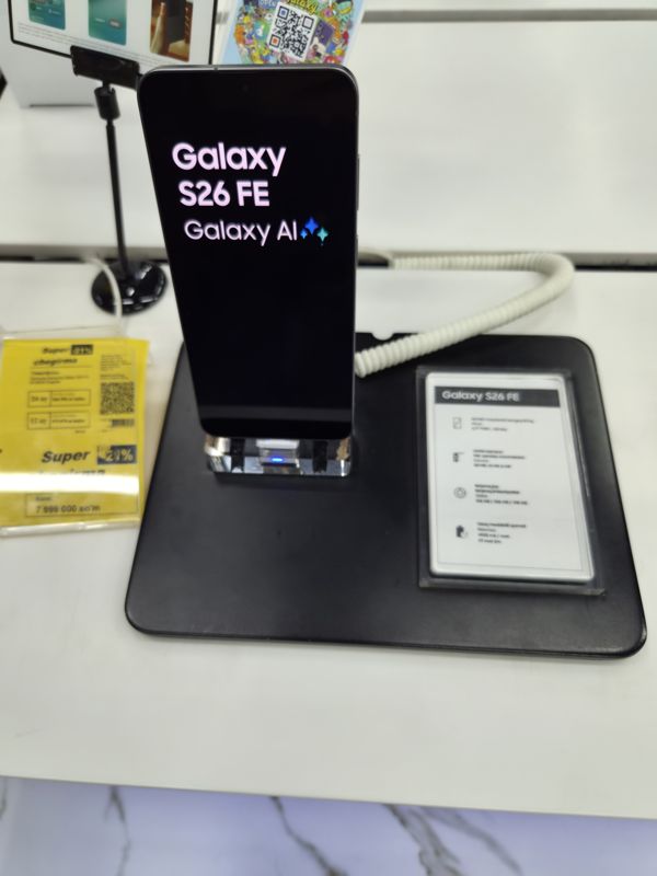 Смартфон Samsung Galaxy S26 FE на подставке в магазине, слева жёлтый ценник «Super chegirma −21%»