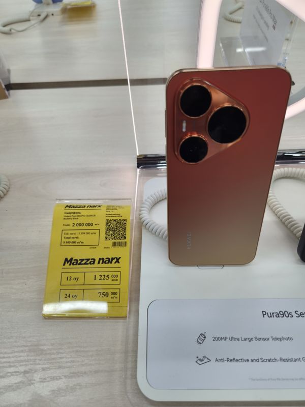 Смартфон Huawei Pura 90s Pro на подставке с кабелем-антикражей, слева жёлтый ценник «Mazza narx» с рассрочкой на 12 и 24 месяца