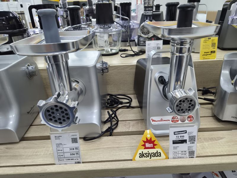 Полка мясорубок в магазине электроники: Moulinex ME858D32 и ME306832 с ценниками, рядом ценники Polaris PMG 2027L и Moulinex со скидкой; сверху на полках блендеры и кухонные комбайны