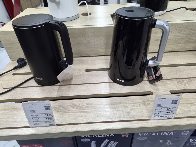 Два чёрных электрочайника Tefal на полке с белыми ценниками магазина электроники