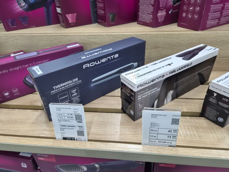Два выпрямителя для волос Rowenta на деревянной полке магазина электроники с белыми ценниками