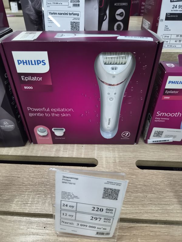 Эпилятор Philips Epilator 8000 в коробке на полке магазина электроники, под ним ценник с моделью BRE730/10