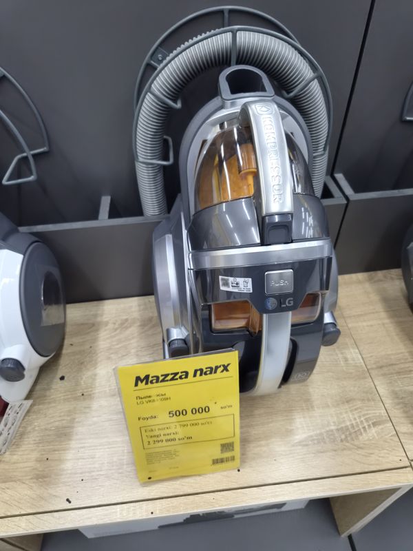 Пылесос LG серии Kompressor с контейнером для пыли и жёлтым ценником «Mazza narx» на полке магазина электроники