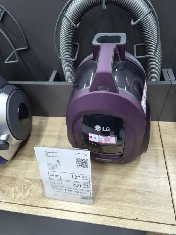 Пылесос LG VC5420NHTW фиолетового цвета с прозрачным контейнером для пыли, надпись 2000W, на полке с ценником магазина электроники
