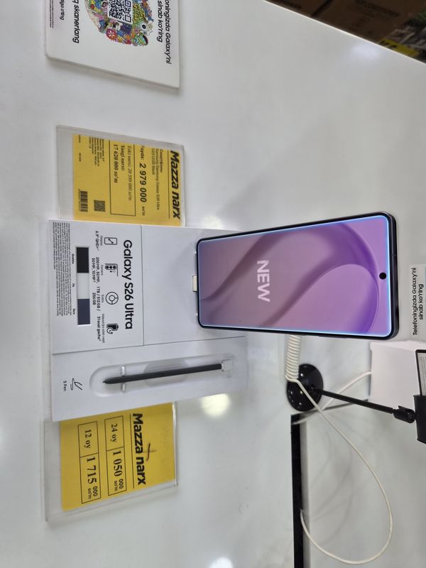 Смартфон Samsung Galaxy S26 Ultra на подставке с карточкой характеристик и S Pen, слева жёлтый ценник «Mazza narx», справа жёлтый ценник «Mazza narx» с рассрочкой на 12 и 24 месяца