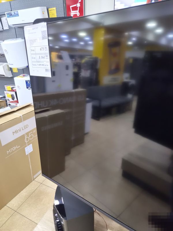 Телевизор LG на подставке в торговом зале Техномарта; на углу экрана ценник с ценой 9 499 000 сум и рассрочкой на 24 и 12 месяцев
