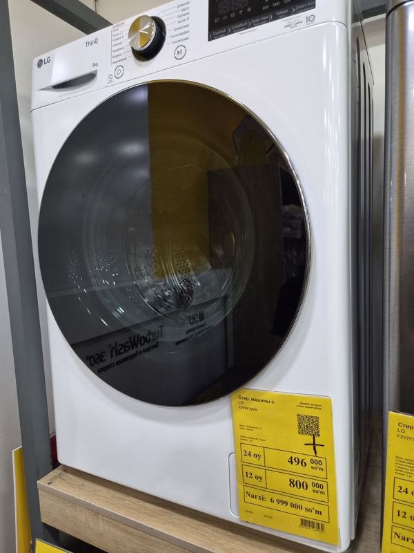 Белая стиральная машина LG F2V9FW9W с загрузкой 9 кг на стенде, внизу справа на корпусе жёлтый ценник Техномарта