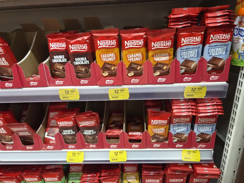 Полка с шоколадом Nestle в Korzinka: Double Chocolate, Caramel & Peanut, Coconut & Waffle с жёлтыми акционными ценниками по 12 990 сум