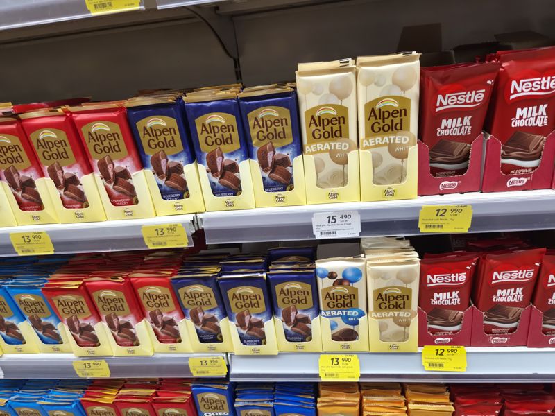 Полка с шоколадом Alpen Gold (клубника-йогурт, черничный йогурт, Aerated white и milk) и Nestle молочный с жёлтыми акционными и белым ценниками
