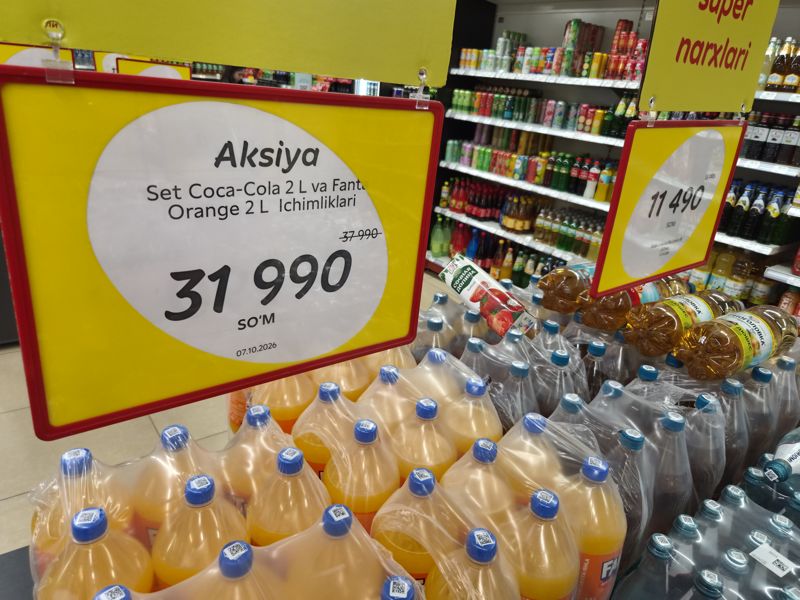 Выкладка газированных напитков и воды в Korzinka: жёлтый ценник «Aksiya» на набор Coca-Cola 2 л и Fanta Orange 2 л и ценник на воду Borjomi с газом