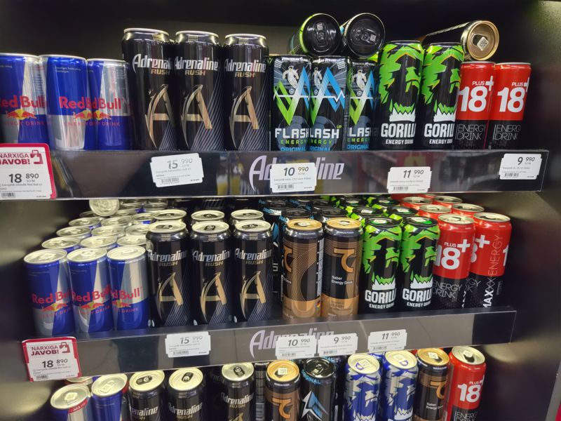 Две полки холодильной витрины с энергетиками Red Bull, Adrenaline Rush, Flash, Gorilla, Saber, 18+ и полочные ценники; слева красная плашка «Narxiga javob» над ценником Red Bull