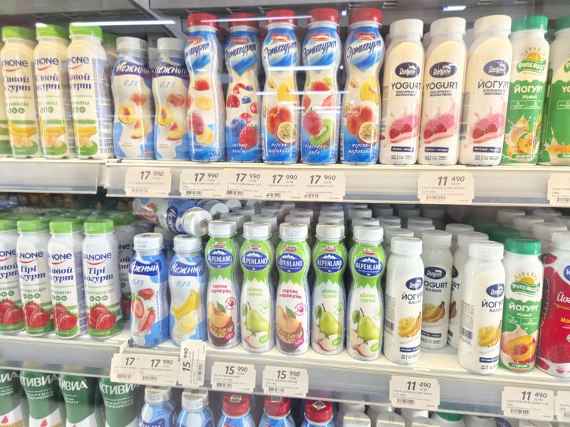 Холодильная полка с питьевыми йогуртами в магазине: Ermigurt, Alpenland, Campina, Нежный, Доброе утро, Puremilky, Danone, с белыми ценниками