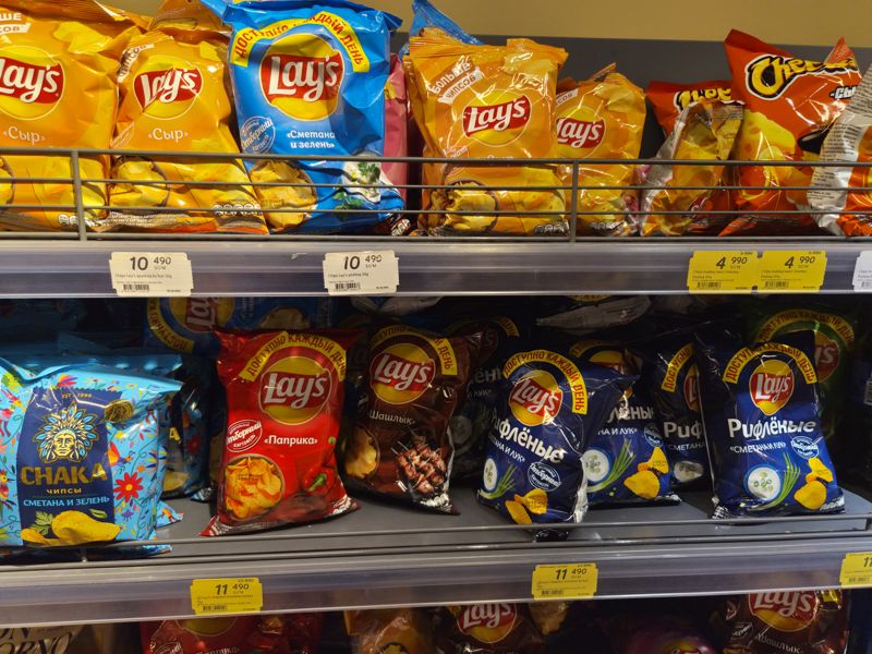 Полки с чипсами Lay's, Cheetos и Chaka, на нижней полке жёлтые акционные ценники
