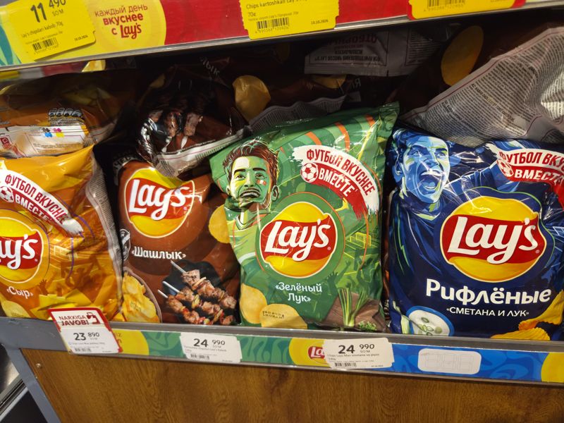 Полка чипсов Lay's Max 140 г в Korzinka: сыр, шашлык, зелёный лук, рифлёные сметана и лук; футбольная серия упаковок