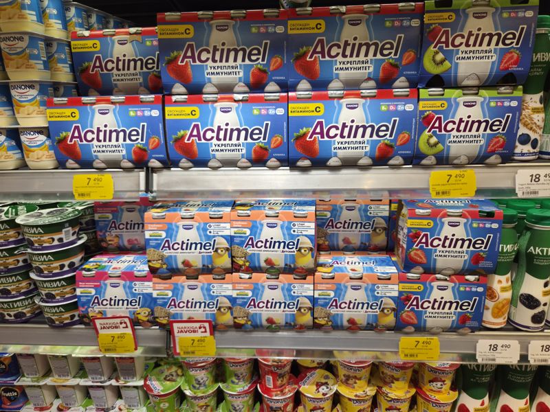 Холодильная витрина питьевых йогуртов Korzinka: Actimel (взрослый и Kids с миньонами), Activia; жёлтые акционные ценники Actimel 7 490 сум и плашки «Narxiga javob!»