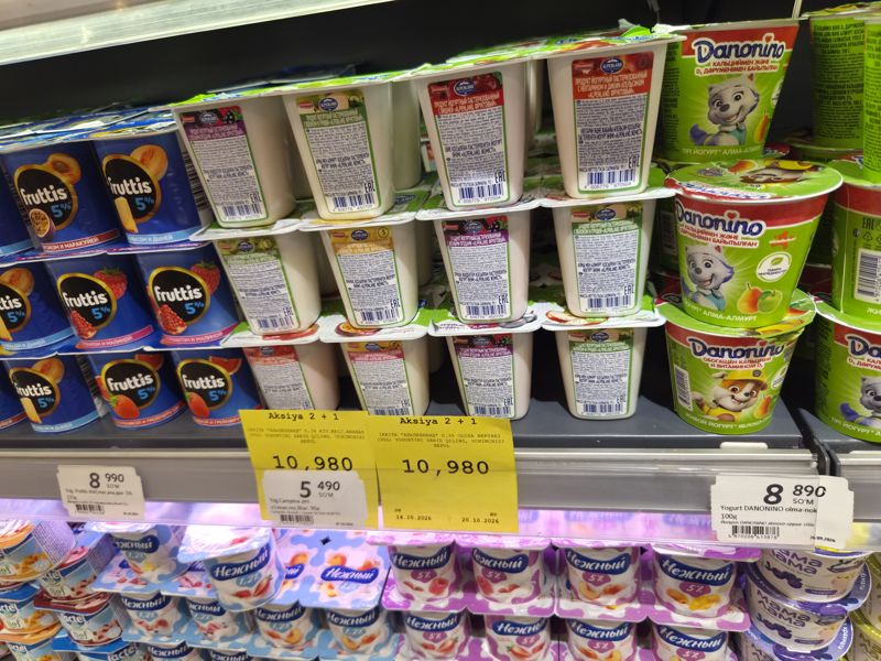 Холодильная витрина йогуртов Korzinka: Alpenland, Fruttis 5%, Danonino, Campina, Нежный; жёлтые плакаты «Aksiya 2 + 1» на йогурты Альпенландъ (14.10–20.10.2026)