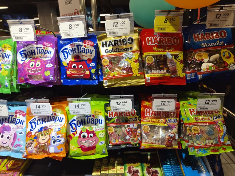 Подвесные пакеты жевательного мармелада на крючках в Korzinka: Haribo (Goldbears, Happy Cola, Starmix, ZOURR Mix / Cola / Worms) и Бон Пари, ценники