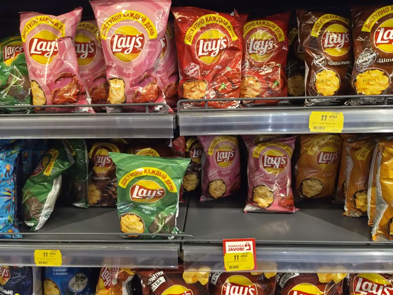 Полки с чипсами Lay's: краб, паприка, шашлык, сыр, зелёный лук; жёлтые акционные ценники и красная плашка «Narxiga javob!»