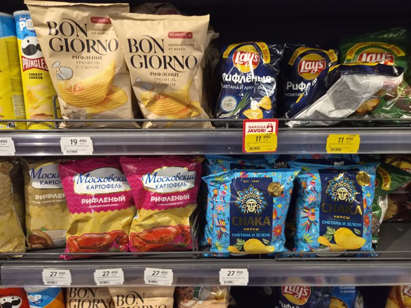 Полки с чипсами: Bon Giorno, Lay's рифлёные, Московский картофель, Chaka, Pringles; ценники с красной плашкой «Narxiga javob!» и жёлтые акционные
