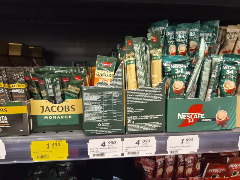 Кофейные напитки в стиках Jacobs и Nescafe 3 в 1 в дисплейных коробках на полке, ценники под ними