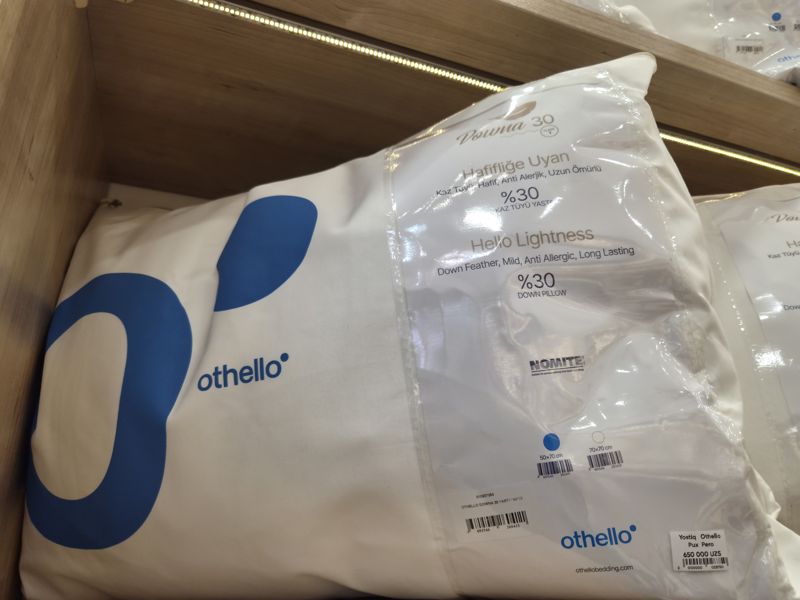 Пуховая подушка Othello Downa 30 в упаковке на полке, на упаковке ценник