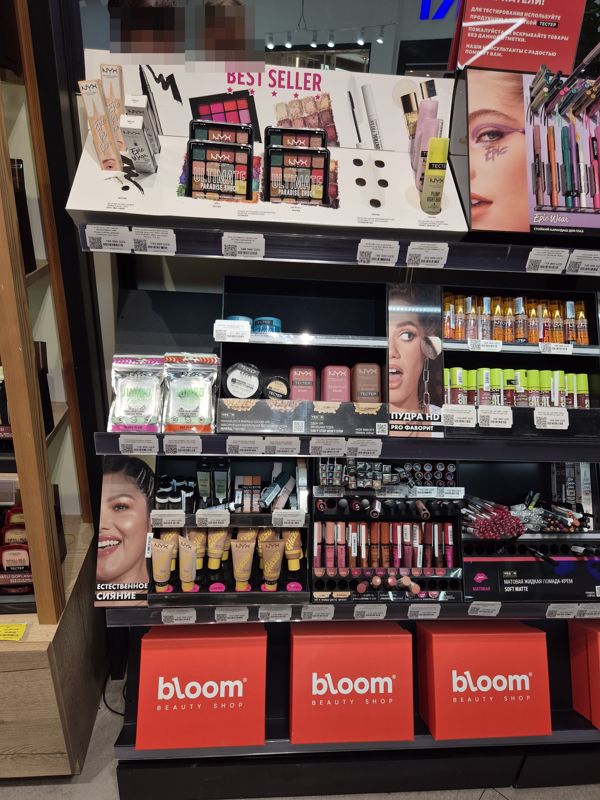 Стенд NYX Professional Makeup: палитры теней, лайнеры, праймеры, румяна, блески и пудры; внизу красные стенды bloom Beauty Shop