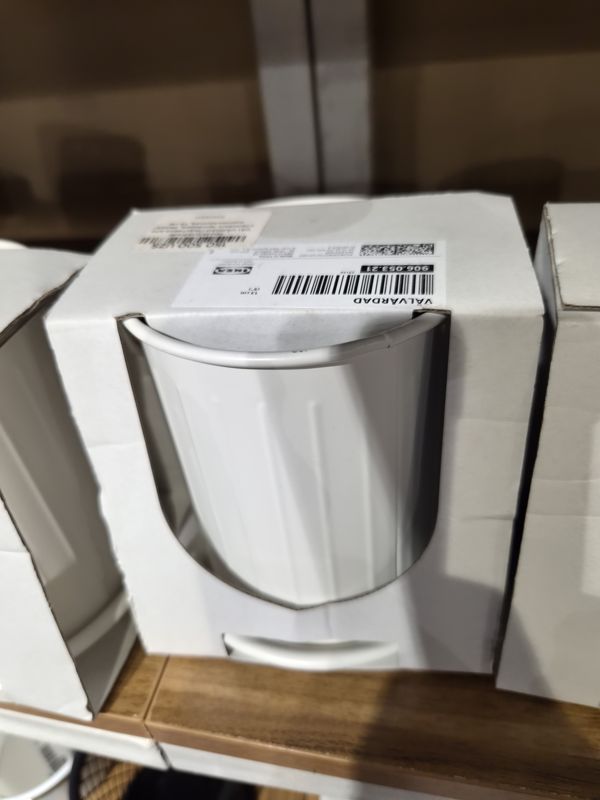 Белое металлическое кашпо IKEA VÄLVÅRDAD 13 см в картонной упаковке с окошком; на упаковке этикетка IKEA и наклейка с ценой, на заднем плане такие же упаковки