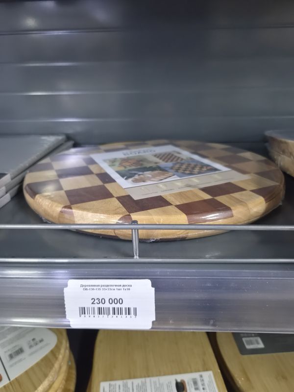 Круглая деревянная разделочная доска-шахматка в плёнке на полке, ниже ценник