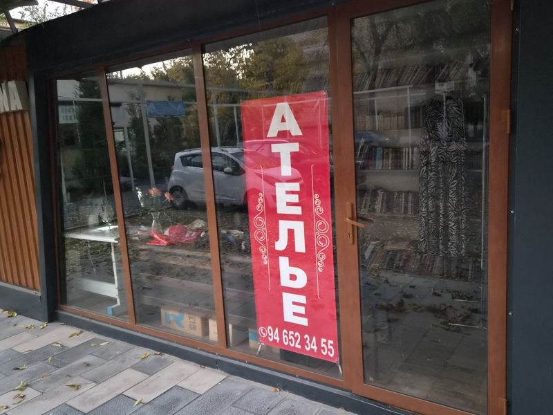 Остеклённая витрина ателье с красным баннером «Ателье» и телефоном